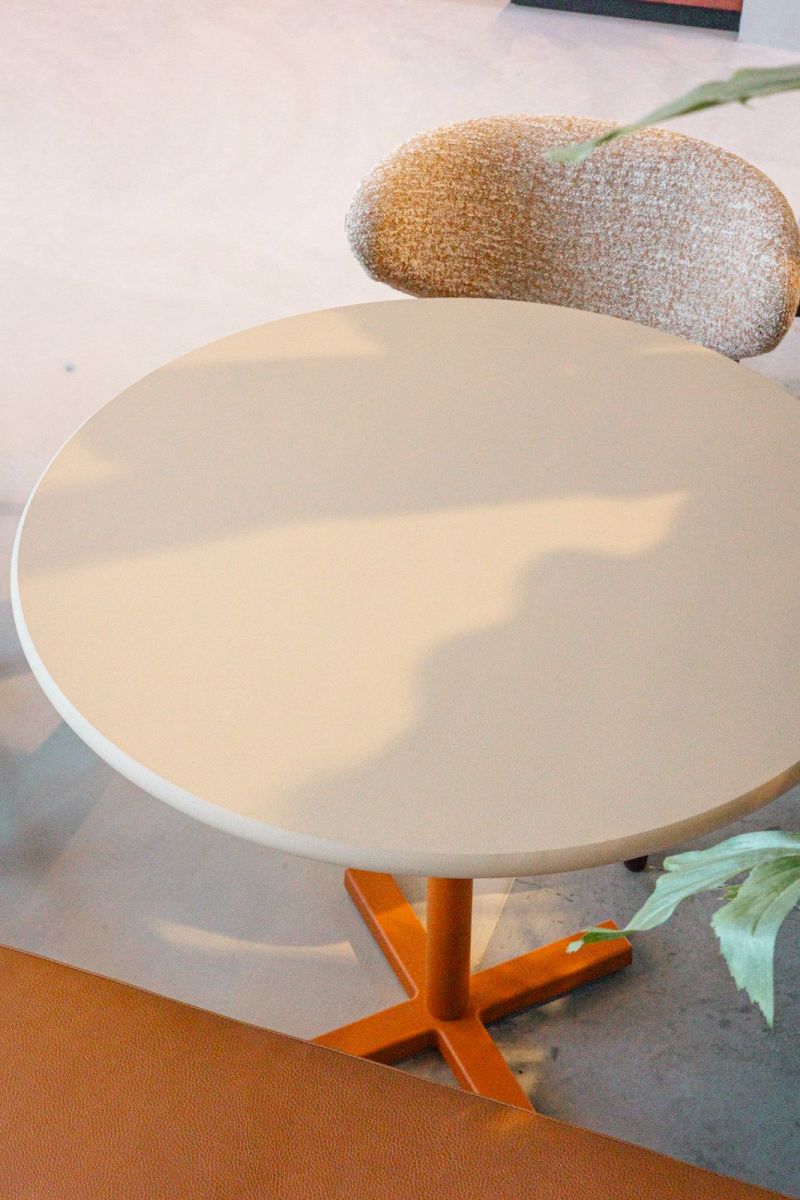 Plateau rond beige à bord arrondi sur un pied orange dans un restaurant