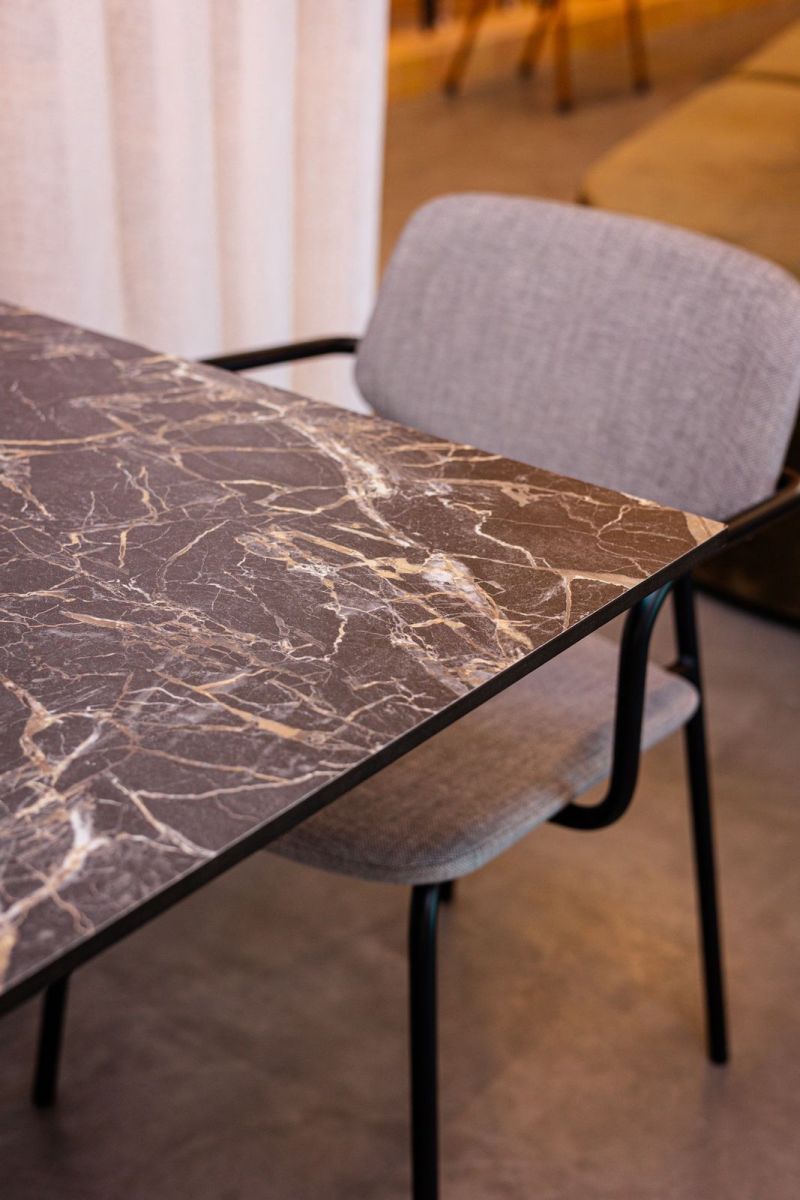 Plateau rectangulaire en décor marbre foncé avec chant noir, une chaise grise à côté